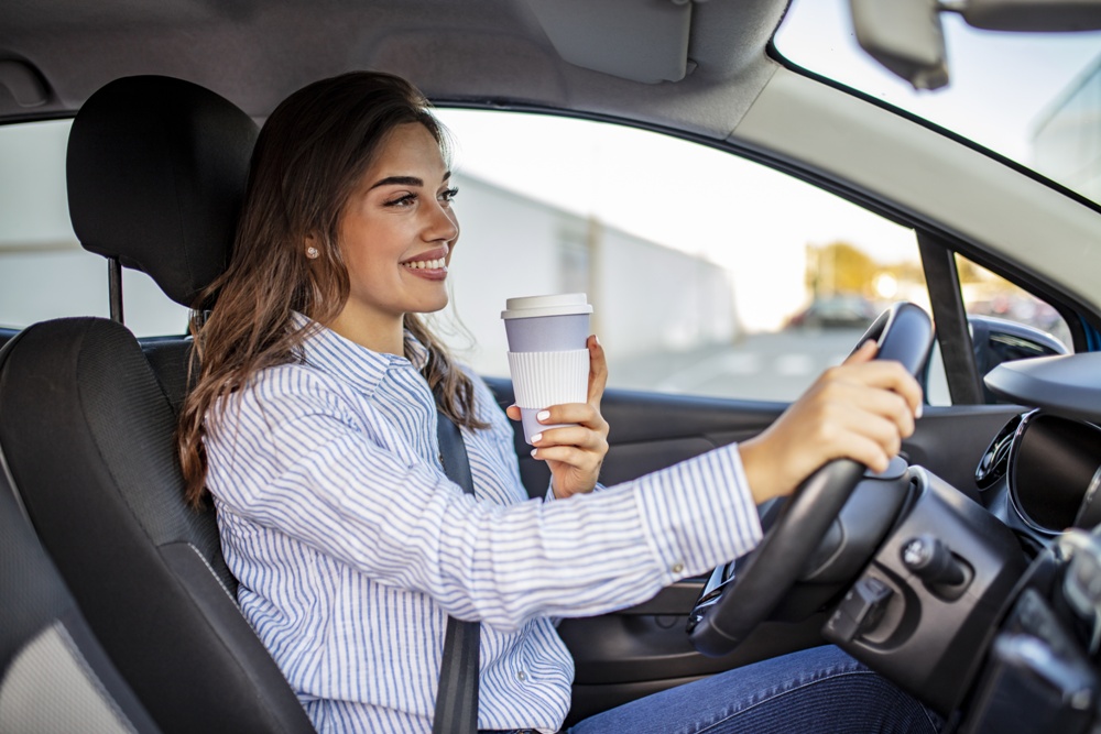 woman driver in her car holding a cup of coffee