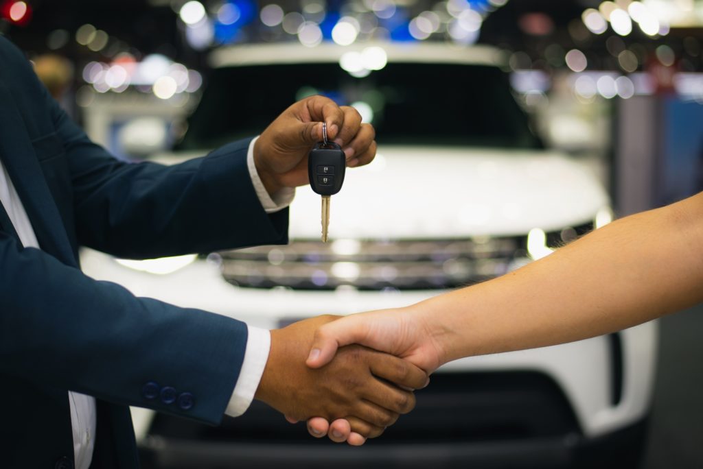 salesman handing over the keys to a customer's new car