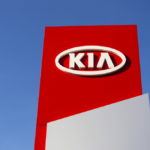 kia motors company logo in front of dealership building