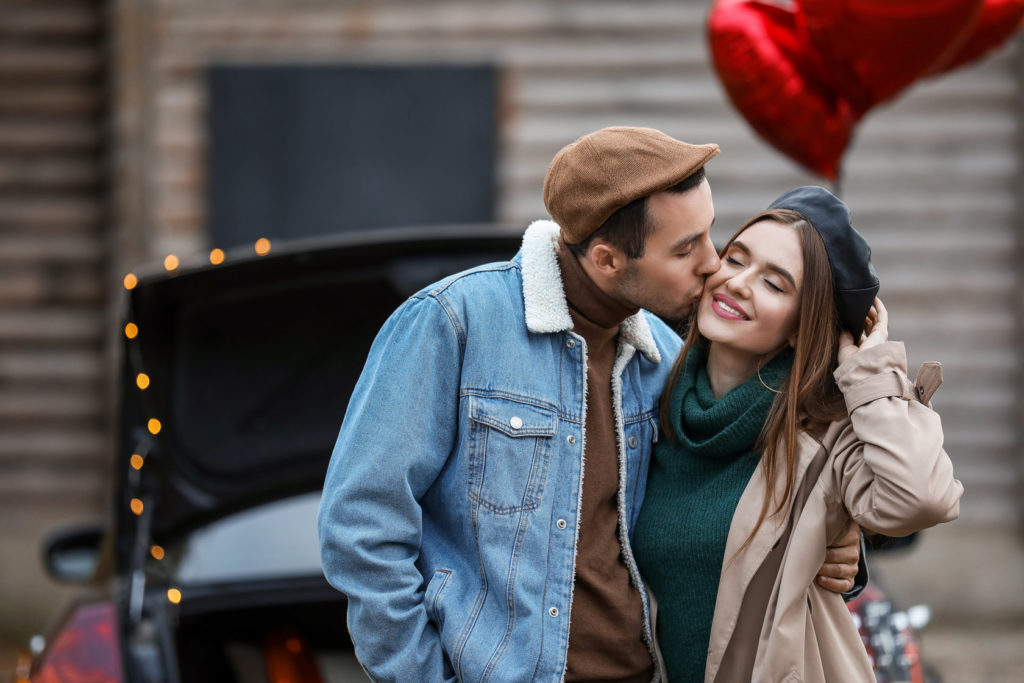 couple in front of car with heart balloons