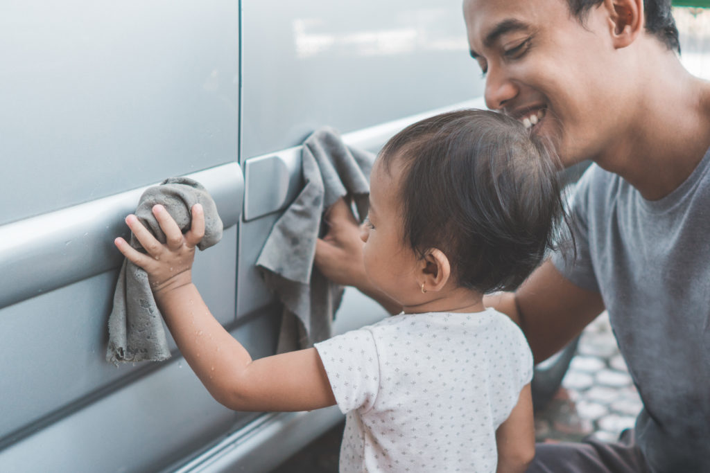 Dad and baby daughter cleaning Mom's car