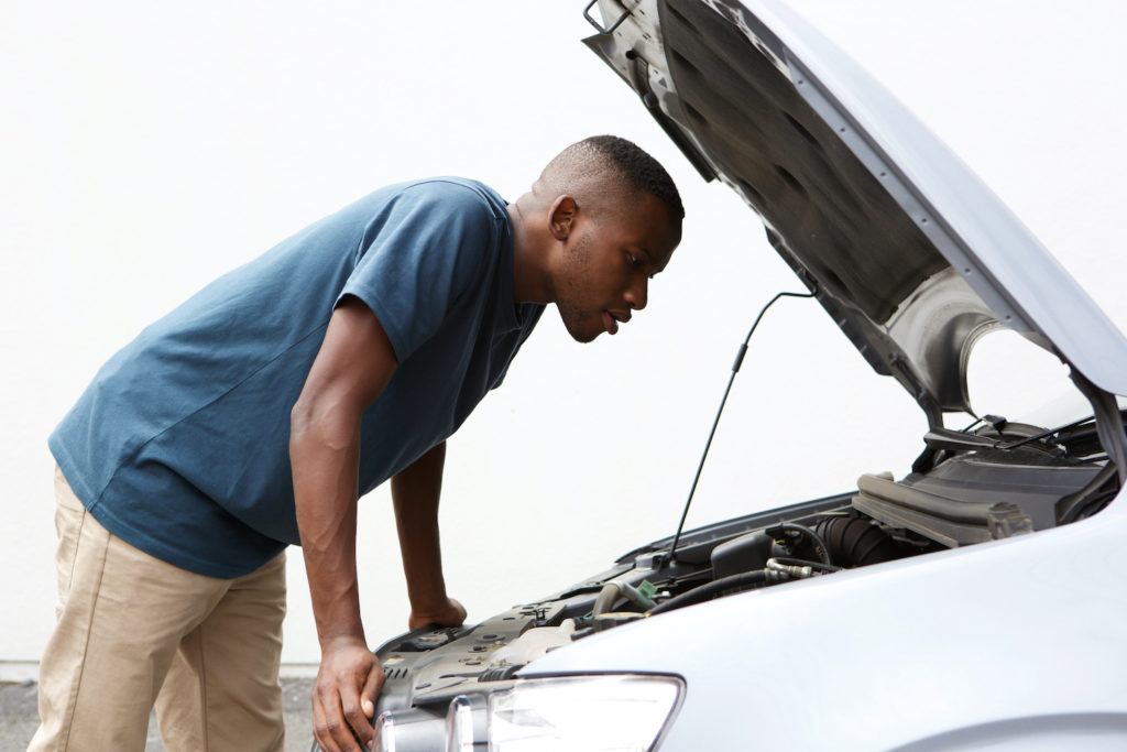 young man checking under the hood of his car