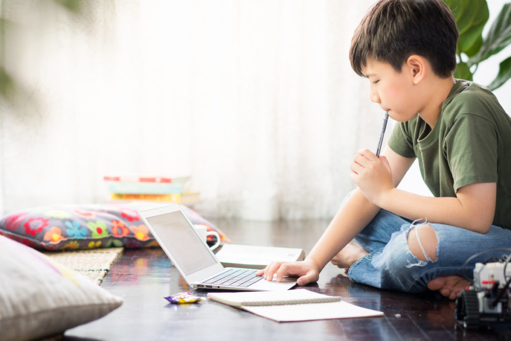 young boy using laptop homeschooling