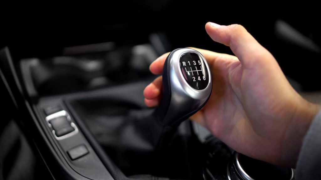 Male hand holding manual transmission gearbox in car