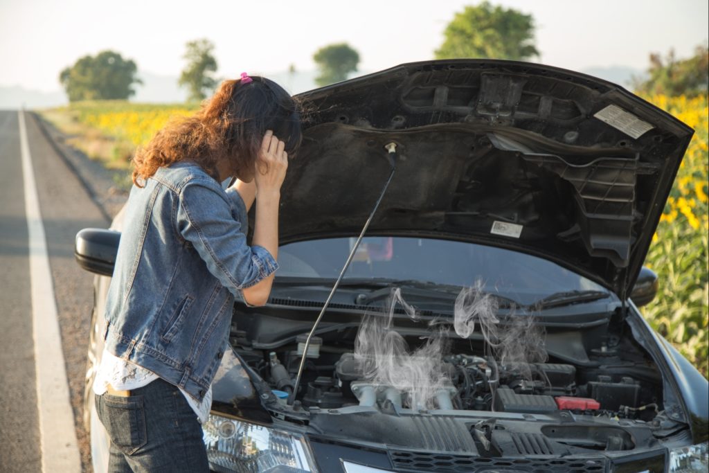 woman staring at an overheating car engine