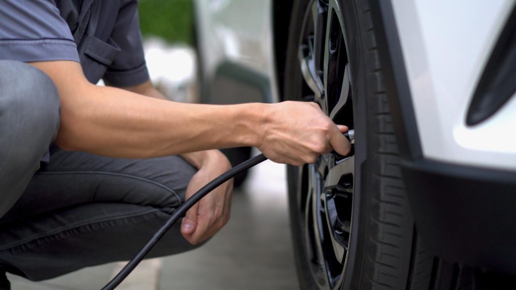 man filling air in the tires of a car