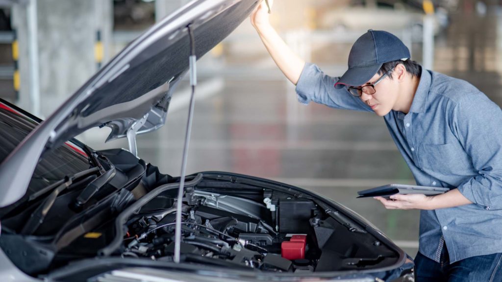 asian male mechanic performs a hood inspection to identify car issues