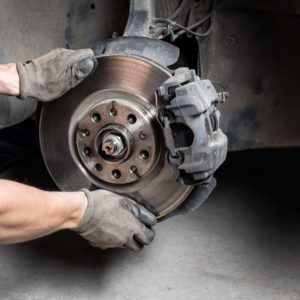 car mechanic hands replace brakes in garage