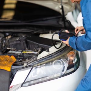 mechanic in blue suit performs inspection on car