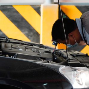 man performs car hood visual inspection of black car