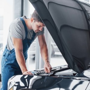 male mechanic looking for issues inside car hood