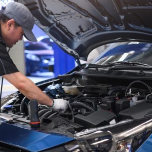 Asian auto mechanic inspects secondary air injection system