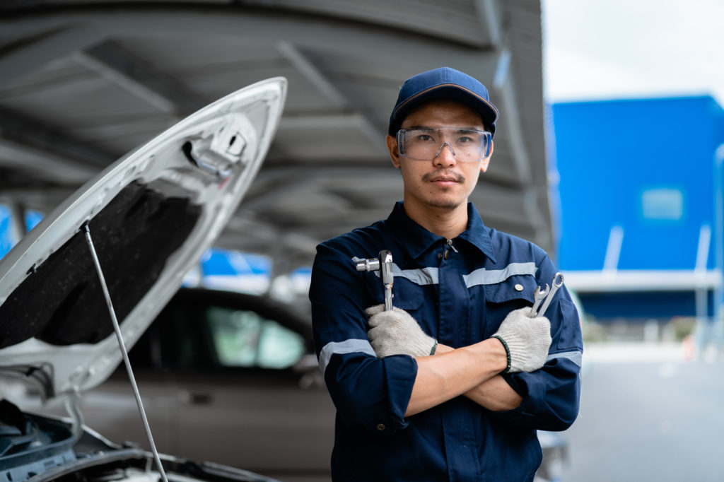 young asian mechanic checking the safety of a car