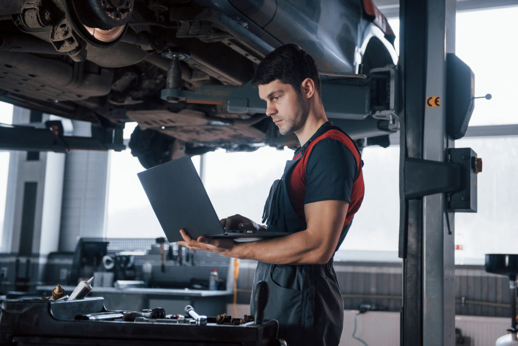 mechanic checks p0702 code with car undercarriage in background