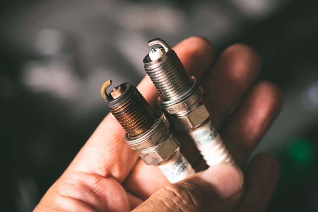 hand holding old and new spark plugs