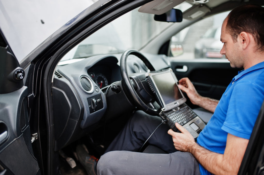 mechanic in blue clothes diagnosing car