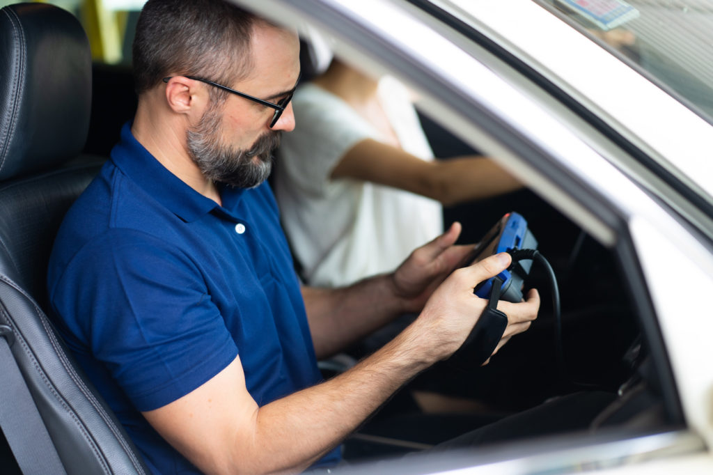 mechanic on car passenger side running obd diagnostic