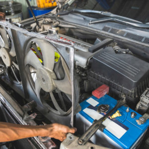 mechanic pulls out car radiator fan for replacement