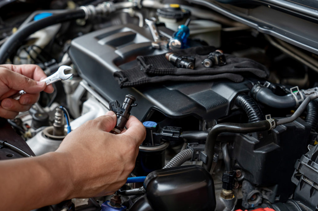 car fuel injector being held by mechanic