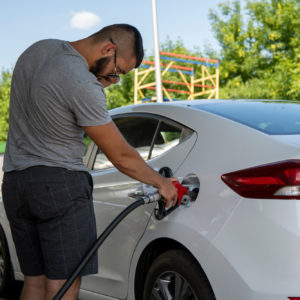 man in gray shirt pumps gas for car