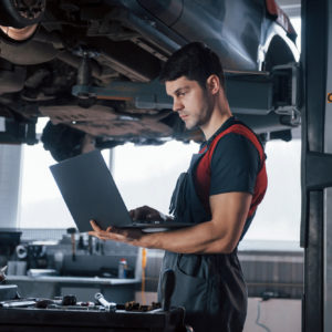 mechanic on foreground with car underchassis visible