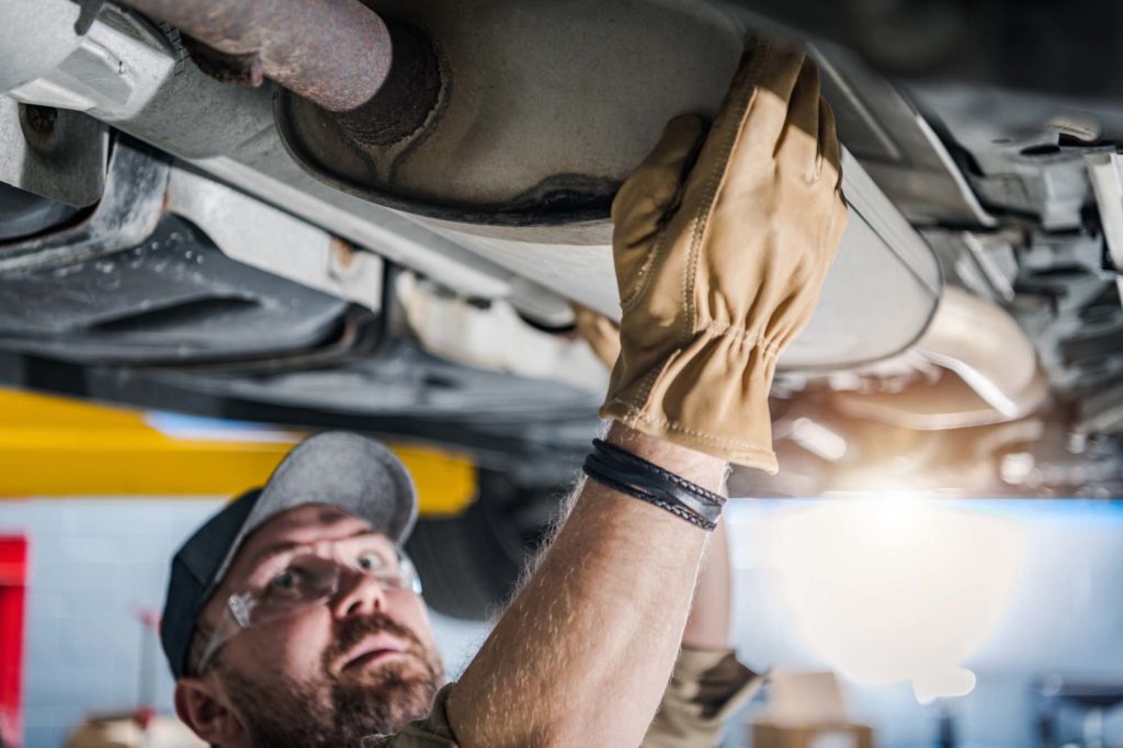 old car catalytic converter being checked by mechanic