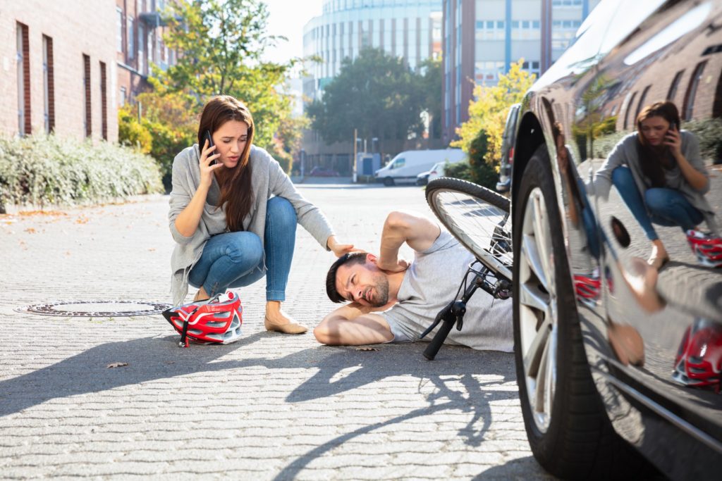 woman inspecting an injured cyclist