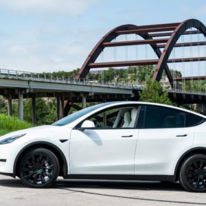 parked tesla model y with a bridge at the background