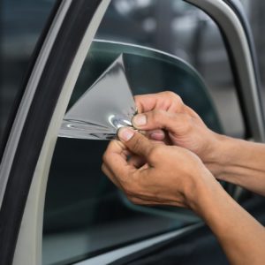 man peeling old car tint film