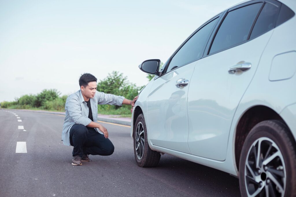 man checking the tire of his car for leaks