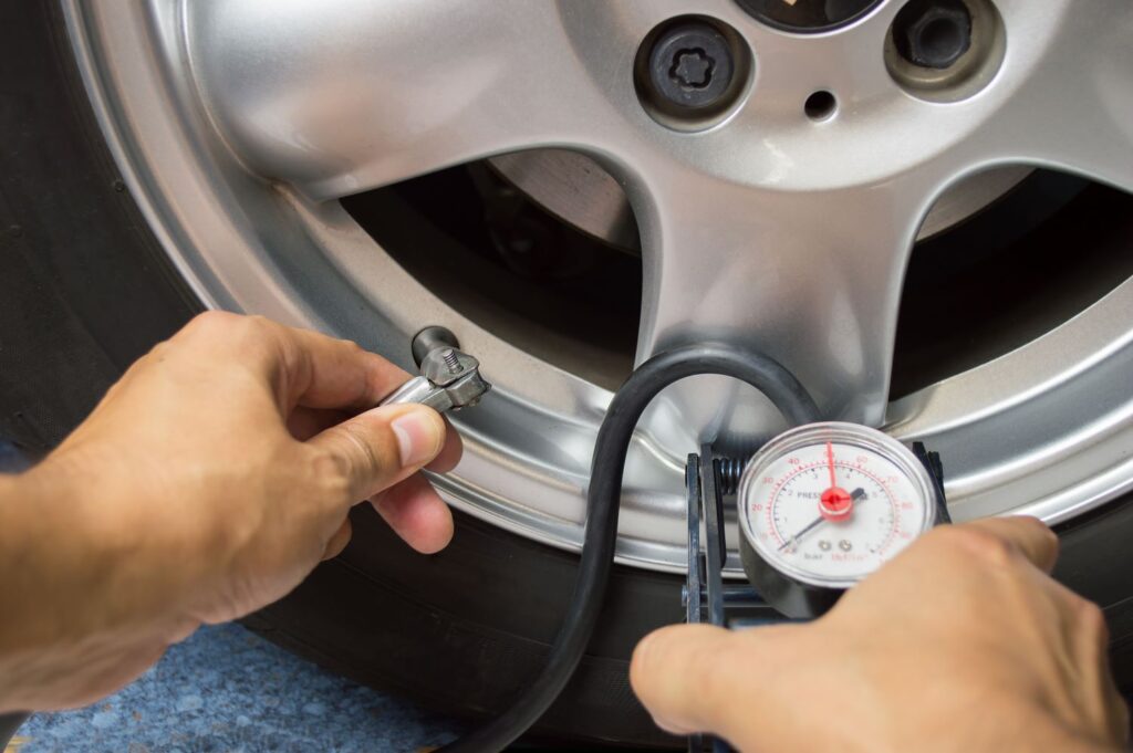 man inflating a tire using a pressure gauge