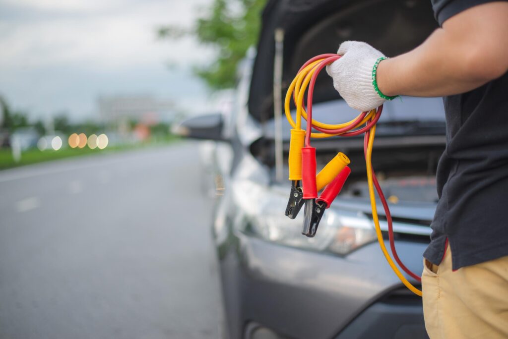 man holding jumper cables for starting car