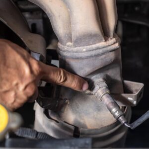 man pointing at old oxygen sensor of car