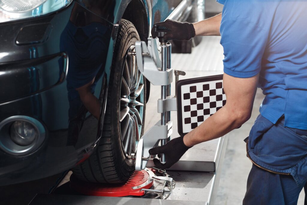 mechanic performs a wheel alignment on car