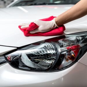 person wiping car hood with a microfiber cloth