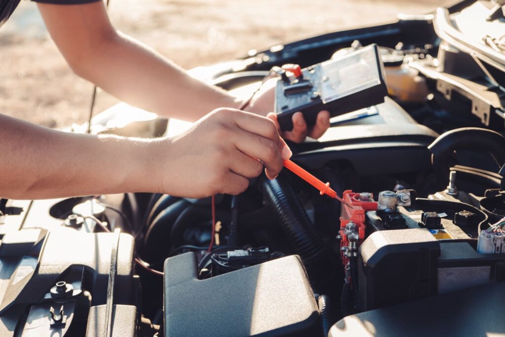 person using a multimeter to check car battery