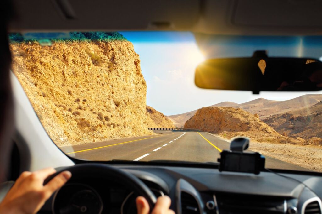 man driving along a desert highway