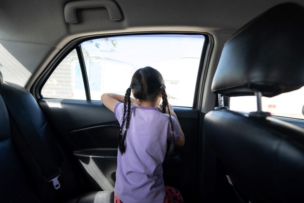 little girl inside a car staring outside