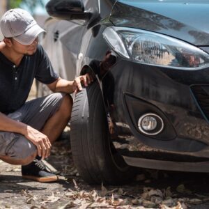 man checking front tire for signs of worn out