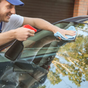 man cleans tinted car windshield windows