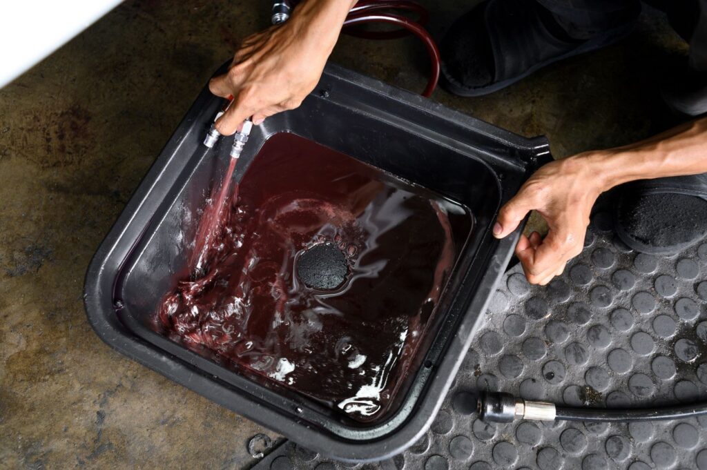 mechanic removing old transmission fluid