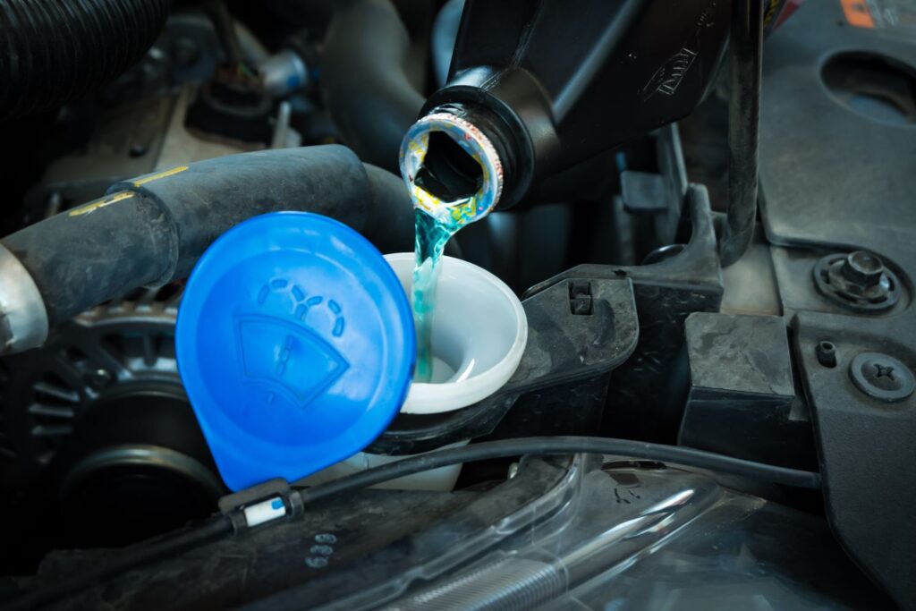 pouring windshield washer fluid to the reservoir