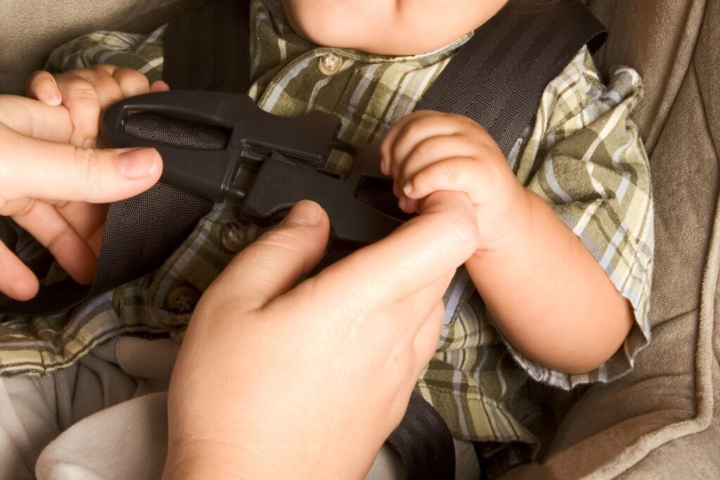 hands attaching chest clip of a car seat