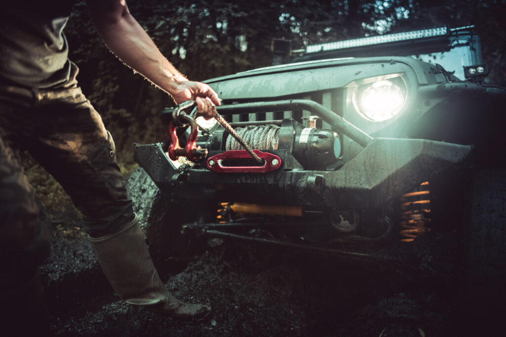 man using car winch to get out of mud