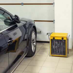 electric fan heater placed between two cars in garage