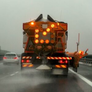 truck pouring road salt on a freeway