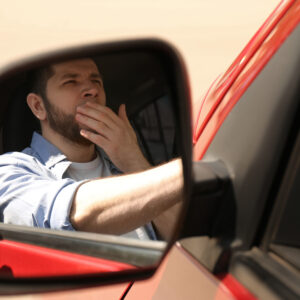 reflection of a man yawning while driving