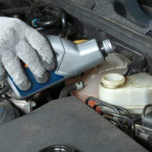 mechanic topping up brake fluid in the vehicle