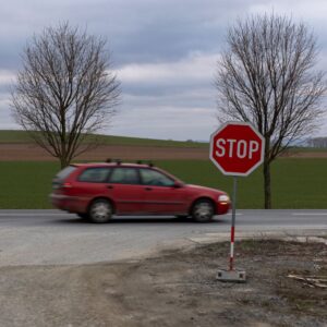 red station wagon on a road with stop sign