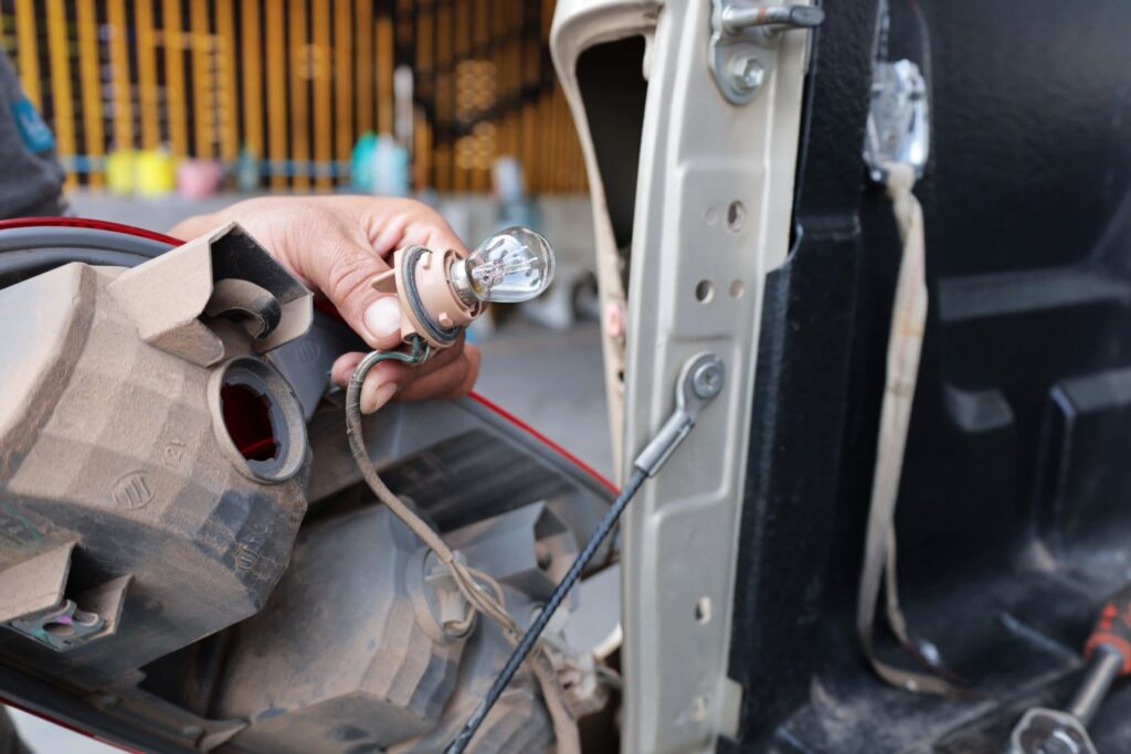 mechanic holding a brake light assembly and bulb